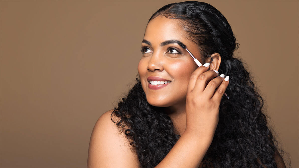 A person uses an eyebrow brush on their face.